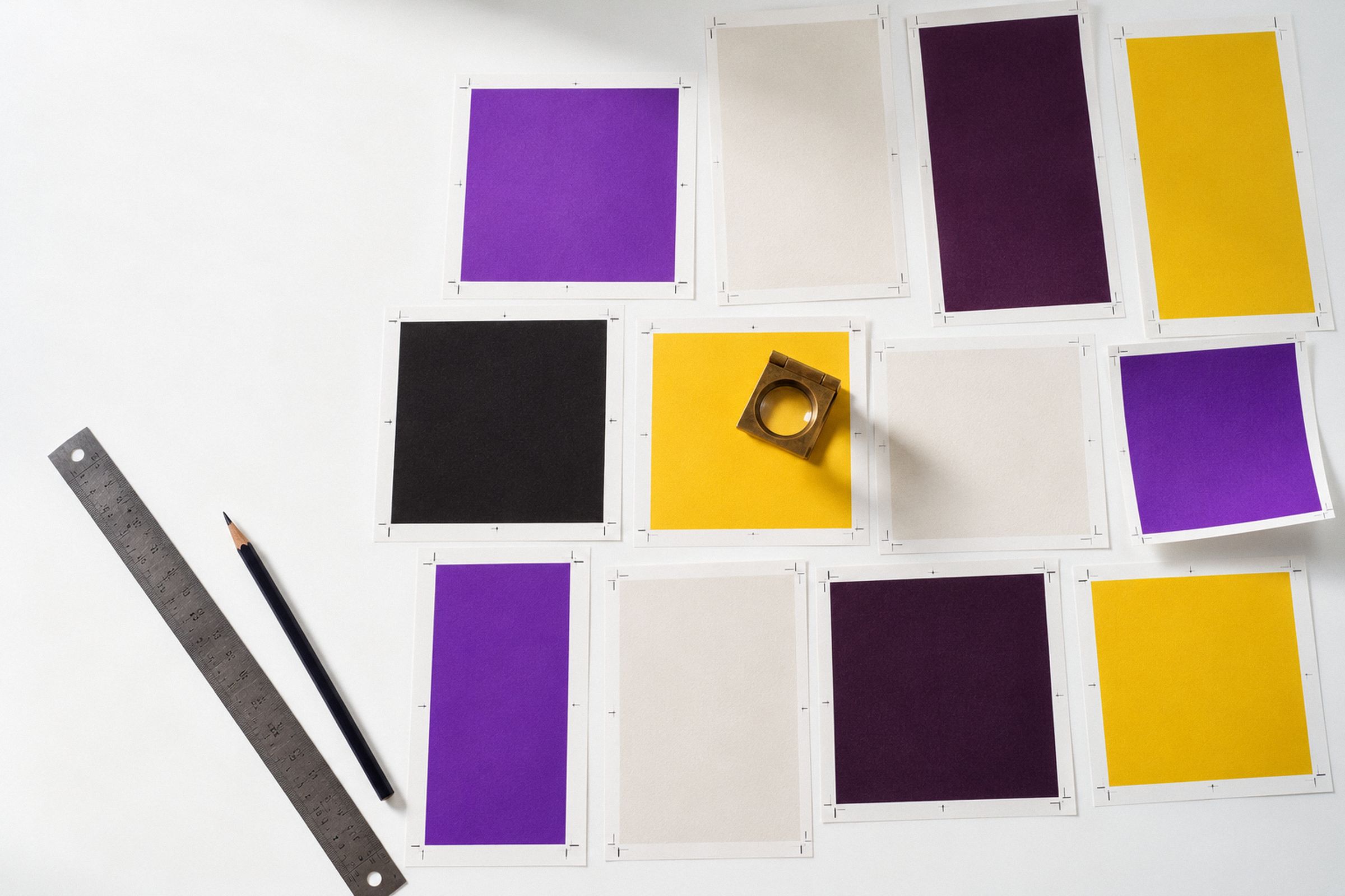 Overhead: blank printed proofs in post, feed and story proportions on a light table, with a loupe and a steel ruler